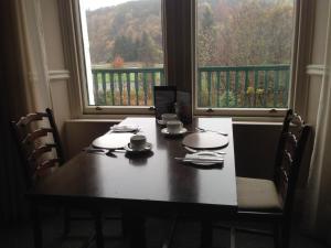 a dining room table with chairs and two windows at Highlander Inn in Craigellachie