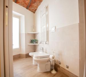 baño blanco con aseo y ventana en BnButler - Alfieri, 15 - Vecchie Atmosfere, en Milán