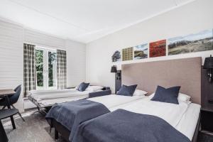 a bedroom with two beds and a desk in it at Frich's Hotell og Spiseri Alvdal in Alvdal