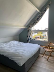 a bedroom with a bed and a window and a chair at Vakantiehuis aan het water in Indijk
