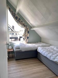 two beds in a room with a window at Vakantiehuis aan het water in Indijk
