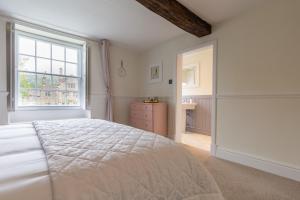 a white bedroom with a bed and a window at Grade II Listed House near Chatsworth in Great Rowsley