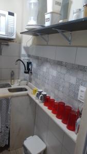 uma cozinha com copos vermelhos num balcão ao lado de um lavatório em Meu Apartamento a 15min de Copacabana no Rio de Janeiro