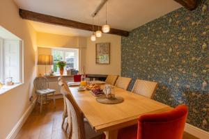 a dining room with a wooden table and chairs at Grade II Listed House near Chatsworth in Great Rowsley