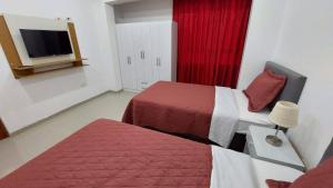 a hotel room with two beds and a television at Departamentos amoblados en Huánuco in Huánuco