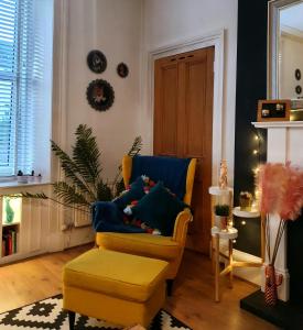ein Wohnzimmer mit einem gelben Stuhl und einer Ottomane in der Unterkunft The Flat with the Pink Door in Edinburgh