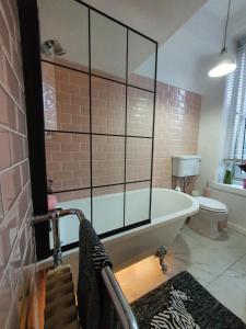 ein großes Bad mit einer Badewanne und einem WC in der Unterkunft The Flat with the Pink Door in Edinburgh