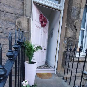 eine weiße Tür mit einer Topfpflanze davor in der Unterkunft The Flat with the Pink Door in Edinburgh
