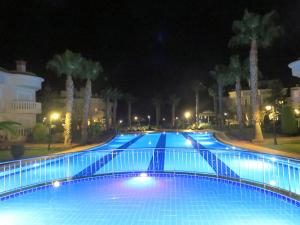 a large swimming pool at night with palm trees at TALYA TURİZM TATİLEVLERİ ve VİLLALARI in Belek