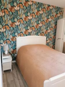 - une chambre avec un lit et un papier peint floral dans l'établissement Gite de la Courtoisie, à Gavray