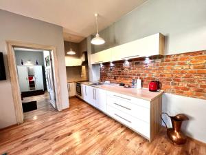 a kitchen with a brick wall and white cabinets at Red&Yellow Apartments Centrum in Olsztyn +49 photos