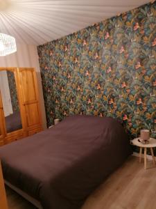 - une chambre avec un lit et un papier peint floral dans l'établissement Gite de la Courtoisie, à Gavray