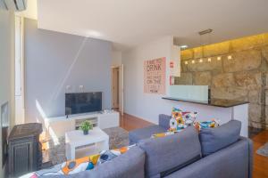 sala de estar con sofá azul y pared de piedra en Feel Porto Ribeira Vintage Duplex, en Oporto