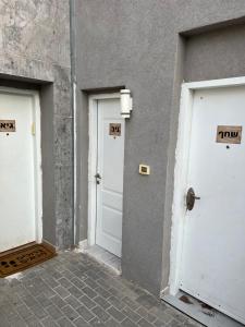 שחף ברוזמרין في إيلات: ثلاثة أبواب بيضاء على جانب المبنى