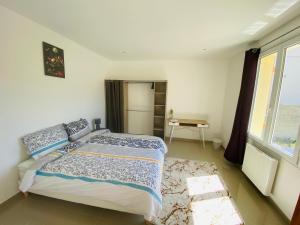 1 dormitorio con cama, mesa y ventana en Maison proche de Paris/CDG et Disney en Villeparisis