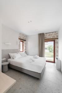 - une chambre blanche avec un grand lit et une fenêtre dans l'établissement Kampus Luxury Villas, à Tríkala