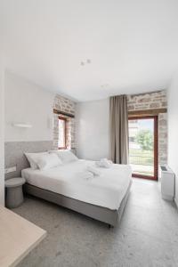 Un dormitorio blanco con una cama grande y una ventana. en Kampus Luxury Villas, en Tríkala
