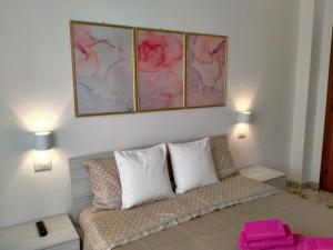 sala de estar con sofá y 3 pinturas en la pared en Le Camelie camera, en Bosa