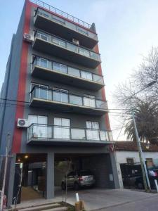 a tall building with a car parked in front of it at Departamento Tigre luminoso frente a club Acohaj in Tigre