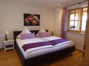 ein Schlafzimmer mit einem großen Bett mit lila Kissen in der Unterkunft Ferienwohnung Schreiner-Viehhausen in Grassau