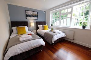 two beds in a room with two windows at Riverwalk Apartment One in Datchet