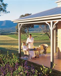 a man and woman sitting at a table on a patio at Berenbell Vineyard Retreat in Pokolbin