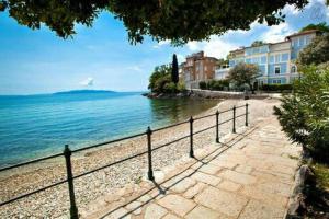 a walkway next to the ocean with buildings and a fence at Apartments Villa Dinka in Opatija