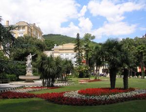 a park with a statue and flowers in front of a building at Apartments Villa Dinka in Opatija