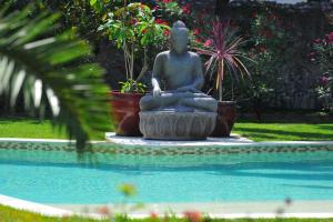 a statue of a woman sitting in a meditation pose next to a pool at Villa Valflor chambres d'hôtes et appartements in Marseille