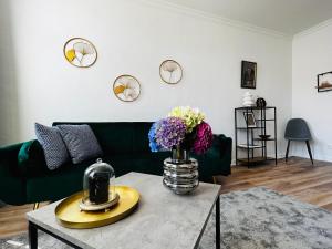 a living room with a green couch and flowers on a table at Das Stader Domizil in Stade