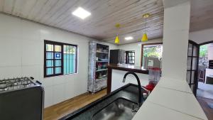 a kitchen with a sink in the middle of a room at Casa Paúba 80m do Mar in Maresias