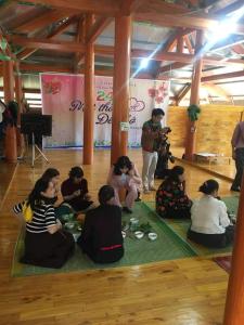 um grupo de pessoas sentadas no chão em uma sala em Xuân nghi homestay em Yen Bai