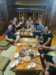 um grupo de pessoas sentadas à volta de uma mesa com comida em Xuân nghi homestay em Yen Bai