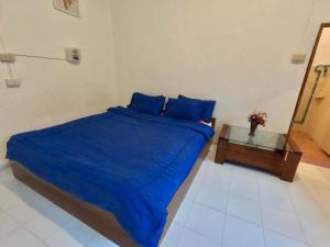 a bedroom with a bed with blue sheets and a table at Sunny garden hostel in Pai