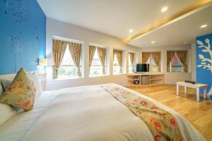 um grande quarto com uma grande cama branca e janelas em Honey House em Luodong