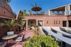 un patio esterno con tavolo e sedie su un edificio di Riad Altair a Marrakech