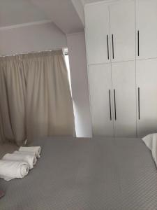 a bedroom with a bed and white cabinets and a window at Alexandra's Apartments - Port of Zante in Zakynthos