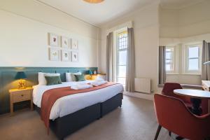 a bedroom with a large bed and a chair at Cliftonville Hotel in Cromer