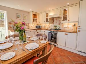 a kitchen with a wooden table with flowers on it at Hill Cottage in Matlock