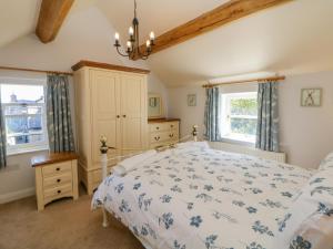 a bedroom with a bed and two windows at Hill Cottage in Matlock