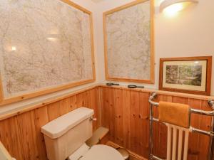 a bathroom with a toilet and maps on the wall at Hill Cottage in Matlock