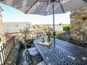 a blue table with an umbrella on a balcony at Hill Cottage in Matlock