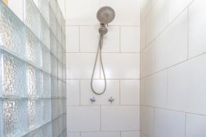 a shower in a white tiled bathroom with a shower head at Playa Hermosa Inn at the beach in Ensenada