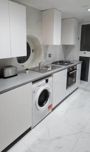 eine Küche mit einer Waschmaschine und einem Waschbecken in der Unterkunft Stunning 2 bedroom apartment in Canary Wharf - Morland Apartments in London