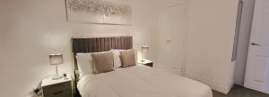 a white bedroom with a bed and two lamps at Stunning 2 bedroom apartment in Canary Wharf - Morland Apartments in London