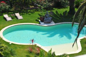 a swimming pool in a yard with two lawn chairs at Villa Valflor chambres d'hôtes et appartements in Marseille