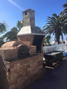 a brick oven with a white fence and palm trees at Casa Palmeral in Mácher