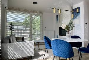 a living room with a table and blue chairs at Pearl Apartment by LoftAffair in Gdańsk