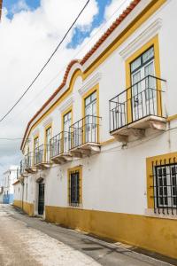 - un bâtiment blanc et jaune avec balcon dans une rue dans l'établissement Eighteen21 Houses - Casa dos Condes, à Cano