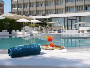 a poolside table with a drink and a glass at Oxygen Lifestyle Hotel in Rimini